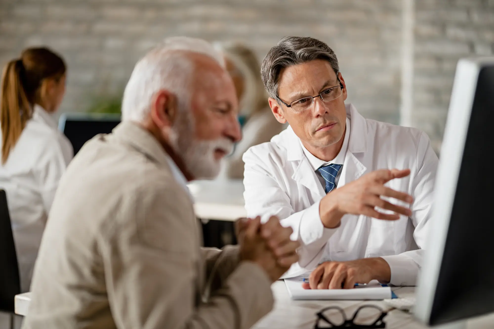 Serious doctor and mature patient examining medical data on computer during a meeting