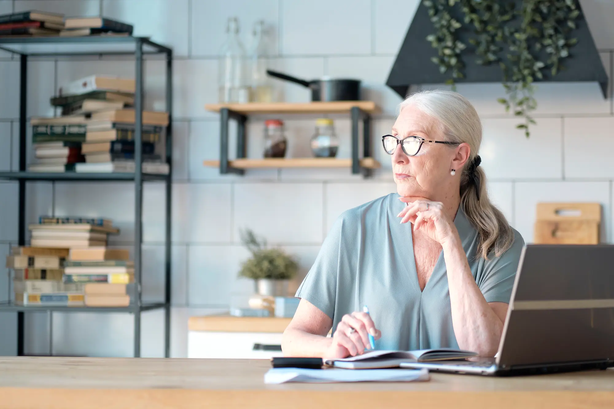 The concept of senior employment, social security. Mature lady sitting at work typing a notebook computer in an home office